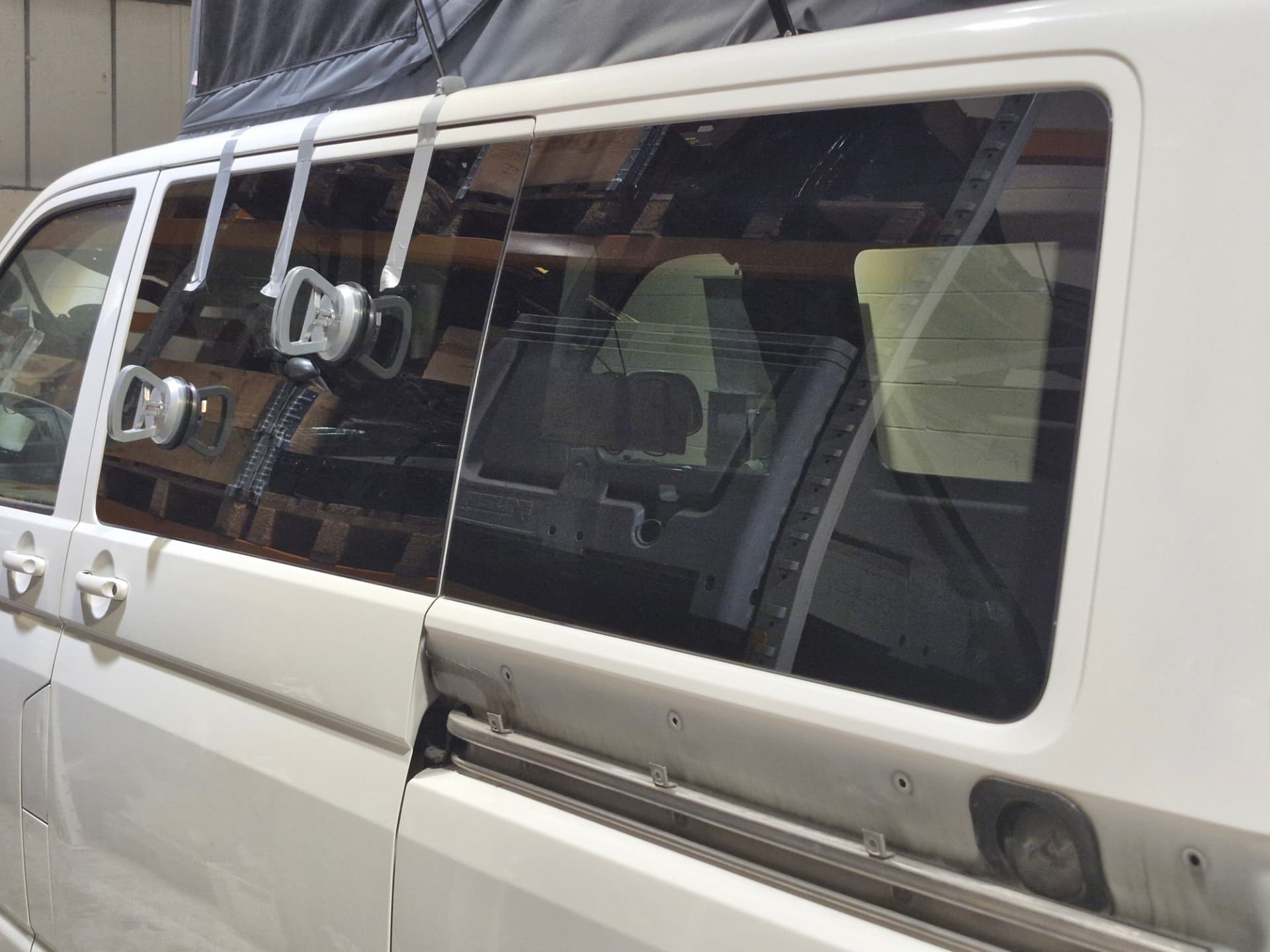 Privacy glass held on suction cups as it is bonded into a cut aperture on a VW Transporter