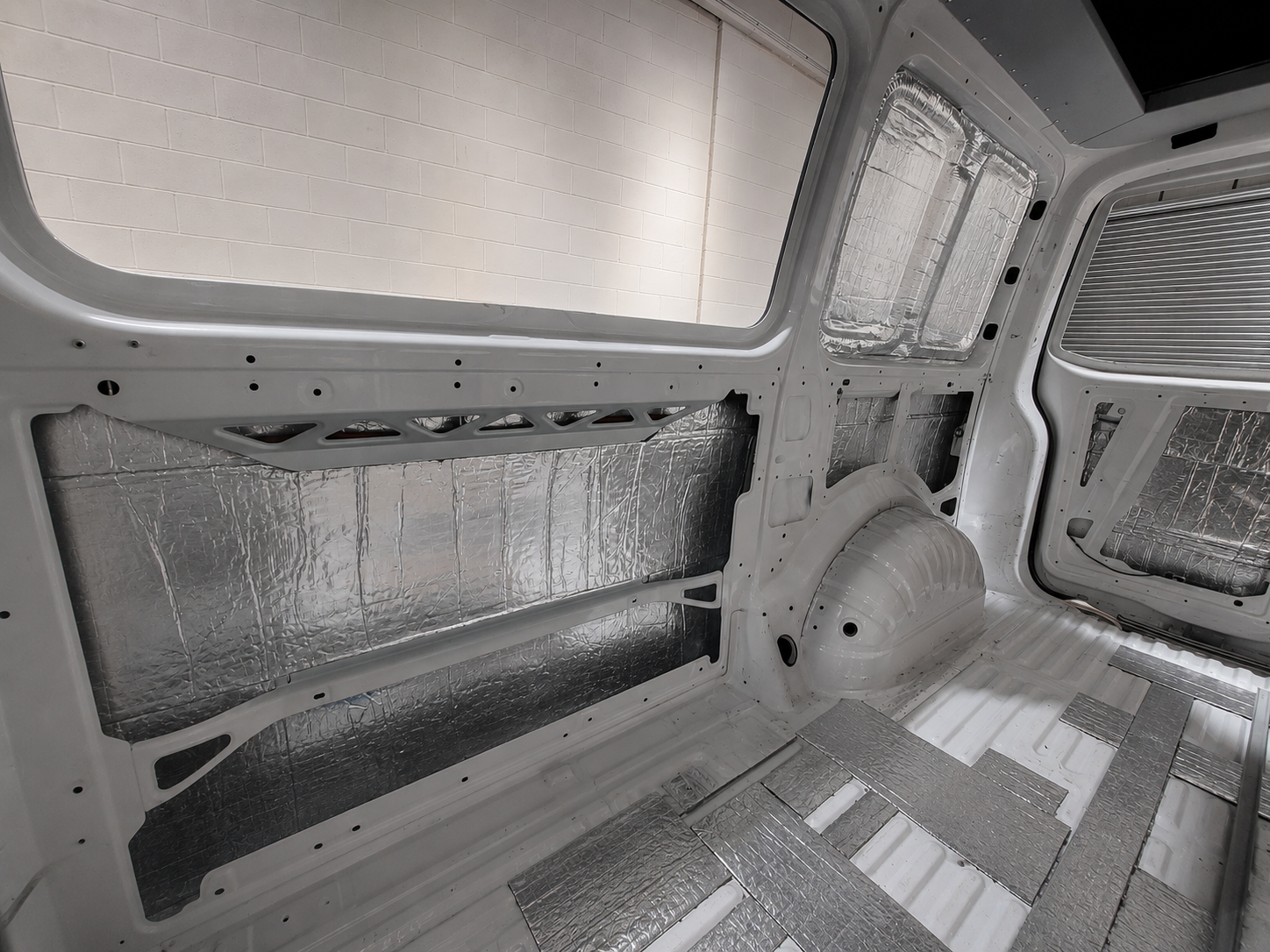 Van interior with sound deadening and insulation panels fitted to the walls and wheel arch